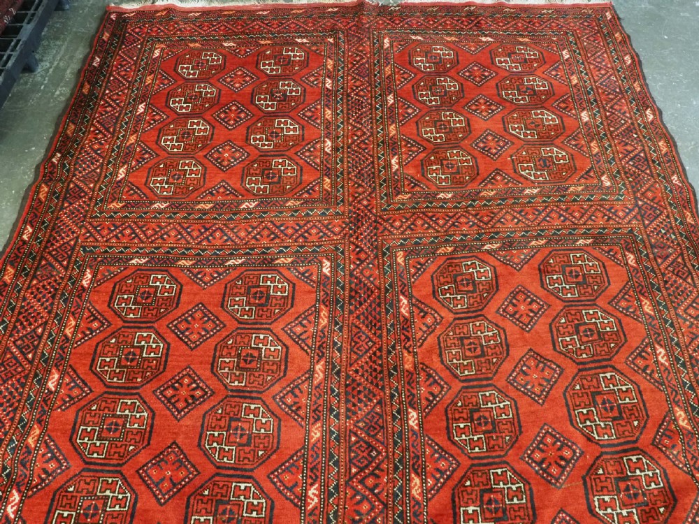 An elongated antique Turkmen Kizil Ayak wool carpet featuring multiple rectangular compartments filled with octagonal geometric guls in deep red, navy blue, and ivory tones. View III