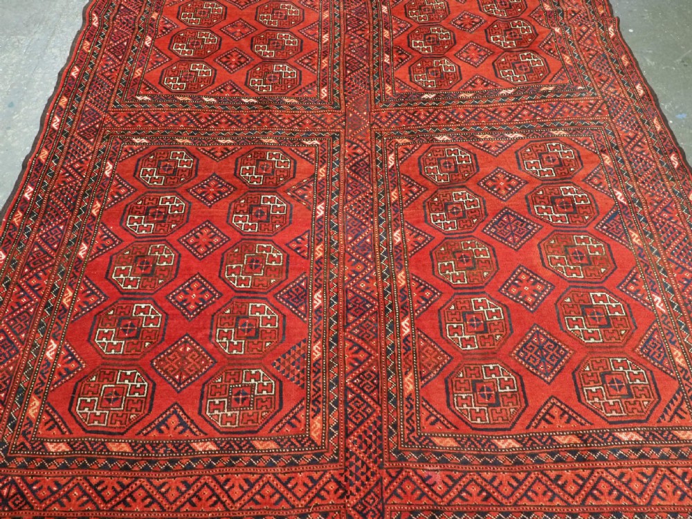 An elongated antique Turkmen Kizil Ayak wool carpet featuring multiple rectangular compartments filled with octagonal geometric guls in deep red, navy blue, and ivory tones. View IV