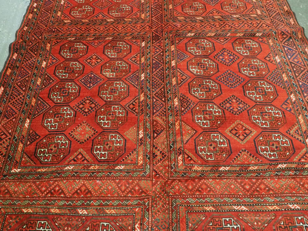 An elongated antique Turkmen Kizil Ayak wool carpet featuring multiple rectangular compartments filled with octagonal geometric guls in deep red, navy blue, and ivory tones. View V