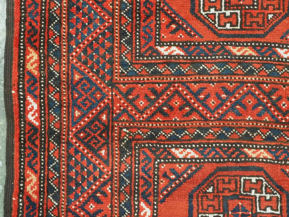 An elongated antique Turkmen Kizil Ayak wool carpet featuring multiple rectangular compartments filled with octagonal geometric guls in deep red, navy blue, and ivory tones. View IX
