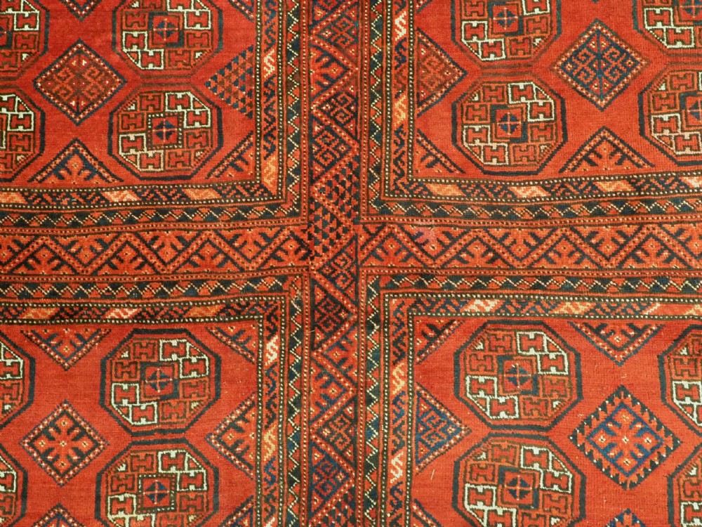 An elongated antique Turkmen Kizil Ayak wool carpet featuring multiple rectangular compartments filled with octagonal geometric guls in deep red, navy blue, and ivory tones. View XI