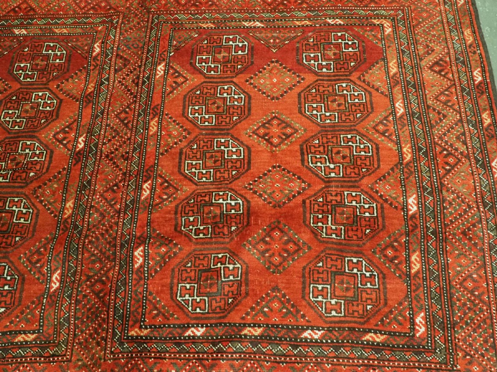 An elongated antique Turkmen Kizil Ayak wool carpet featuring multiple rectangular compartments filled with octagonal geometric guls in deep red, navy blue, and ivory tones. View XIII