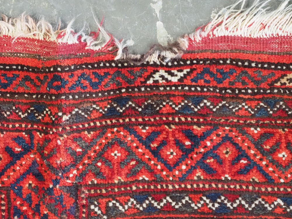An elongated antique Turkmen Kizil Ayak wool carpet featuring multiple rectangular compartments filled with octagonal geometric guls in deep red, navy blue, and ivory tones. View XV