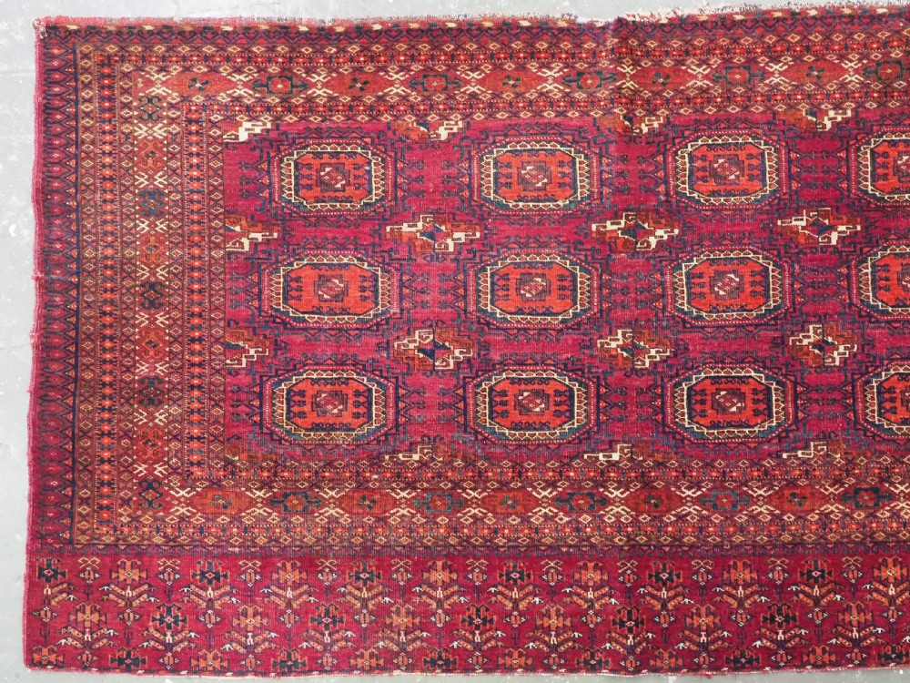 An antique woven crimson wool Tekke Turkmen chuval face featuring twelve octagonal turreted guls arranged in a rectangular grid. View II