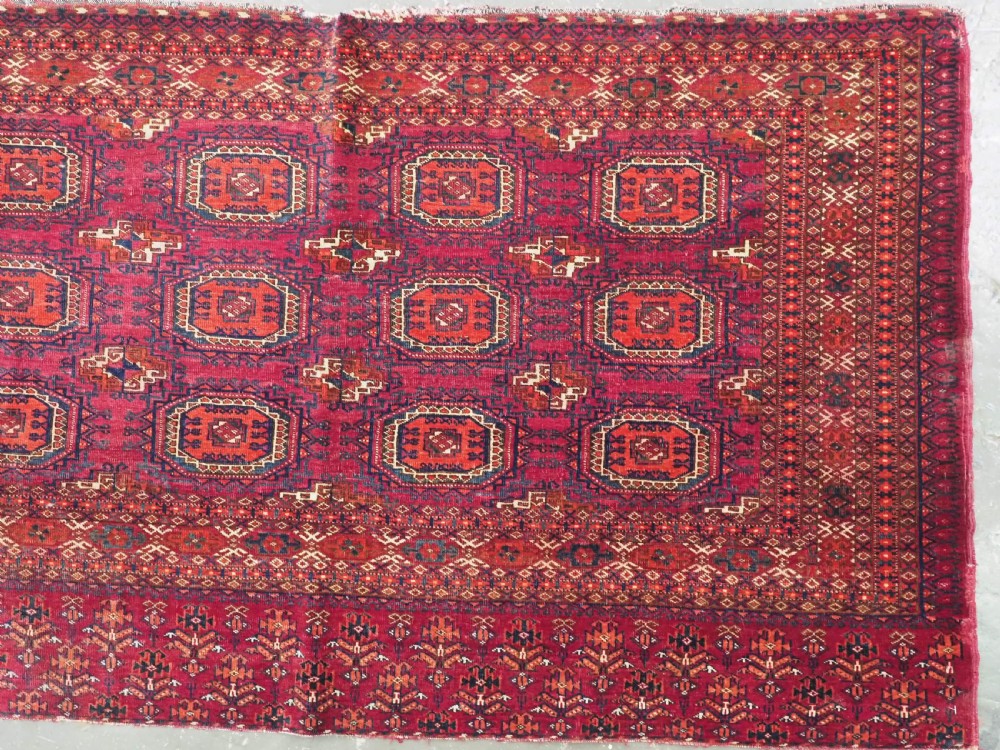 An antique woven crimson wool Tekke Turkmen chuval face featuring twelve octagonal turreted guls arranged in a rectangular grid. View III