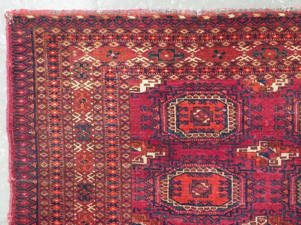 An antique woven crimson wool Tekke Turkmen chuval face featuring twelve octagonal turreted guls arranged in a rectangular grid. View IV
