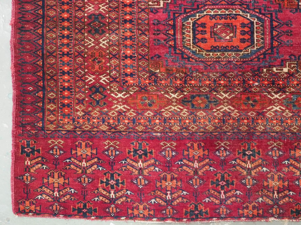 An antique woven crimson wool Tekke Turkmen chuval face featuring twelve octagonal turreted guls arranged in a rectangular grid. View V