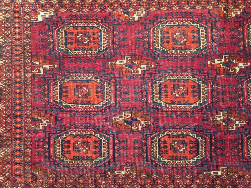 An antique woven crimson wool Tekke Turkmen chuval face featuring twelve octagonal turreted guls arranged in a rectangular grid. View VI