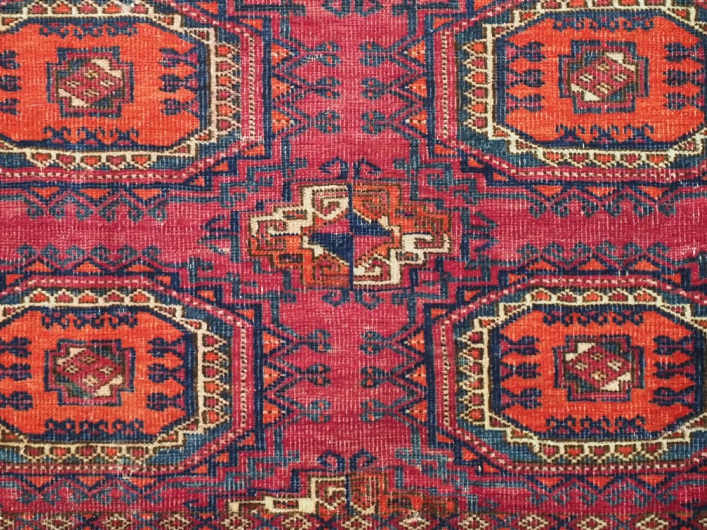An antique woven crimson wool Tekke Turkmen chuval face featuring twelve octagonal turreted guls arranged in a rectangular grid. View VIII