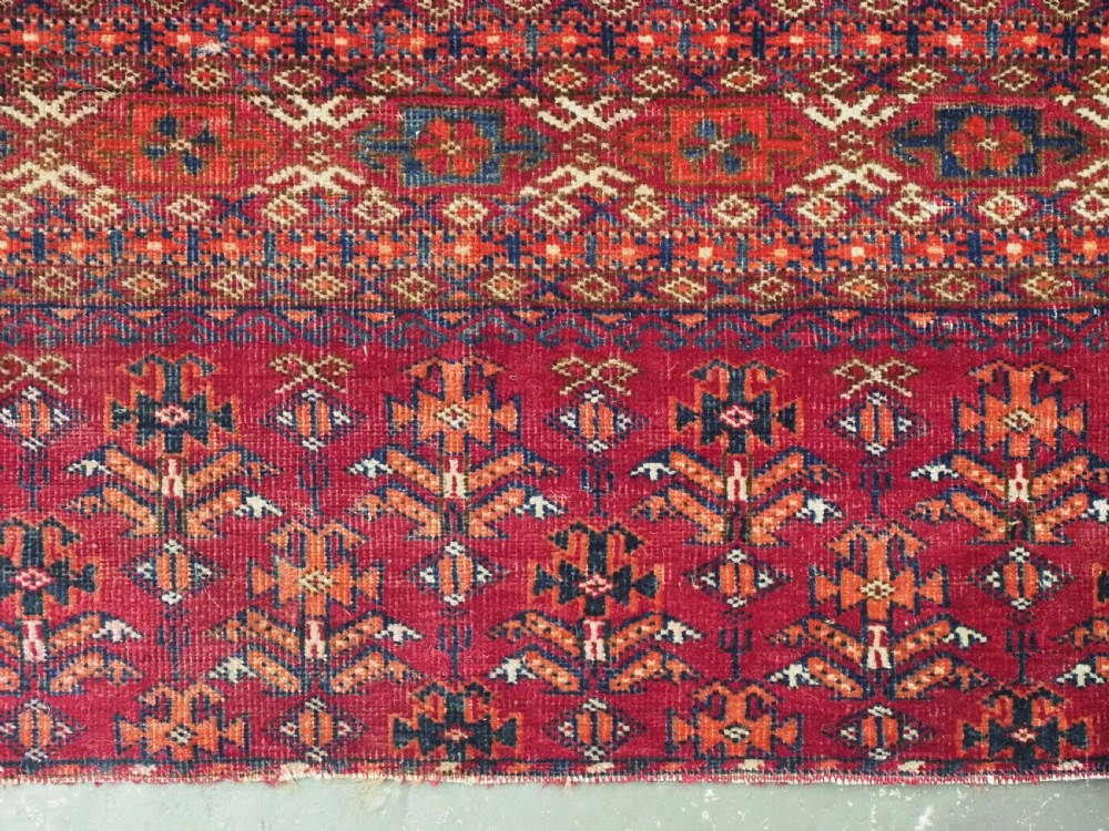 An antique woven crimson wool Tekke Turkmen chuval face featuring twelve octagonal turreted guls arranged in a rectangular grid. View IX