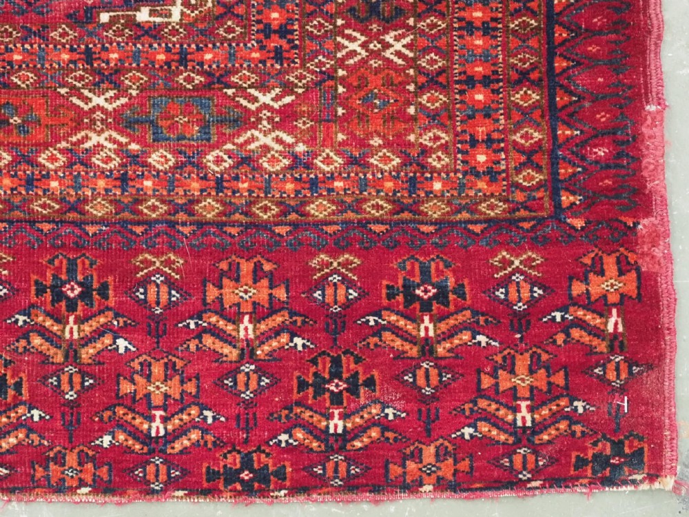 An antique woven crimson wool Tekke Turkmen chuval face featuring twelve octagonal turreted guls arranged in a rectangular grid. View XI