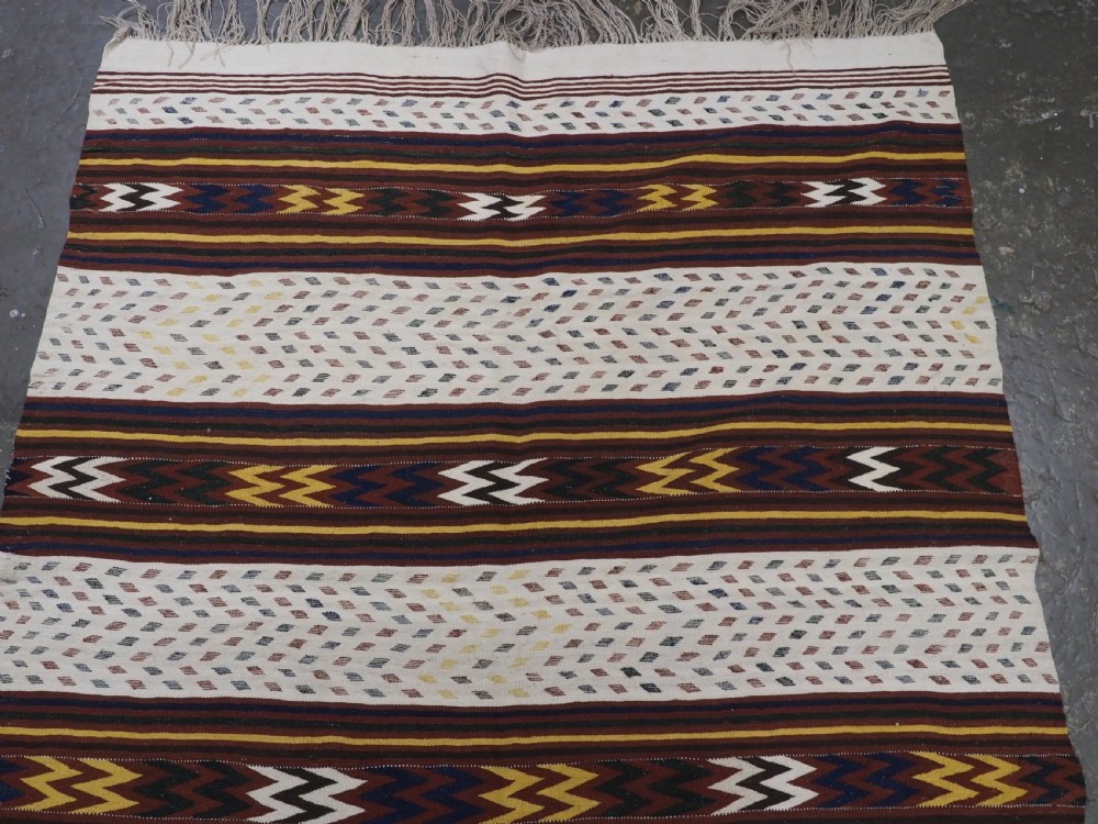 A long handwoven flatweave Central Asian kilim runner displaying cream sections alternating with dark brown, yellow, and red geometric bands with fringe at both ends. View III