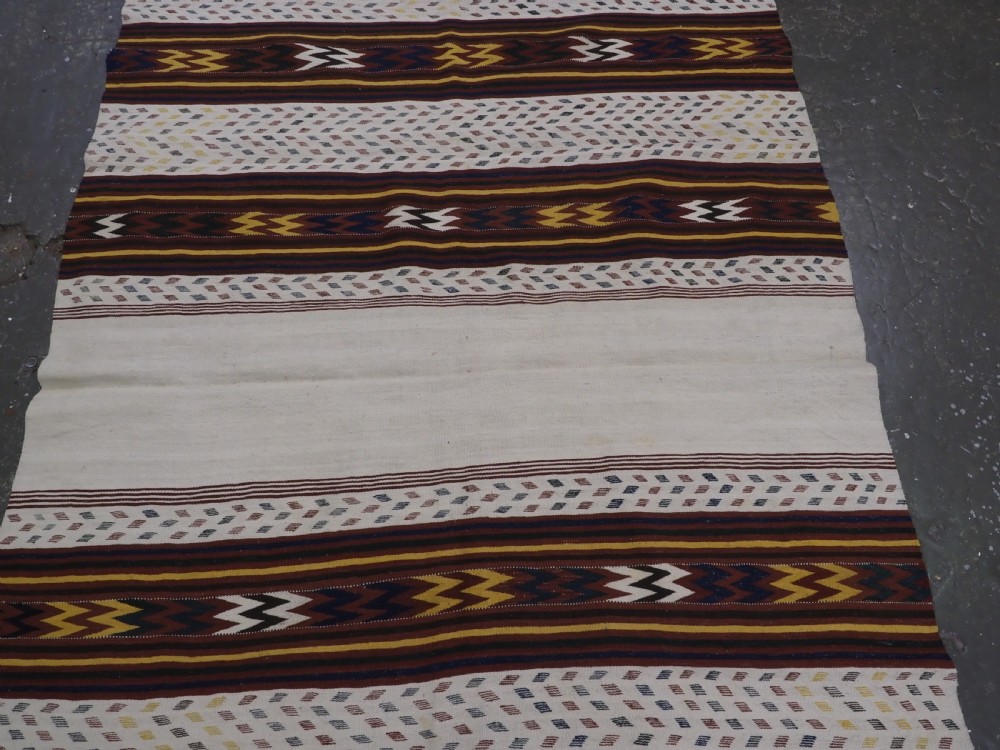 A long handwoven flatweave Central Asian kilim runner displaying cream sections alternating with dark brown, yellow, and red geometric bands with fringe at both ends. View V