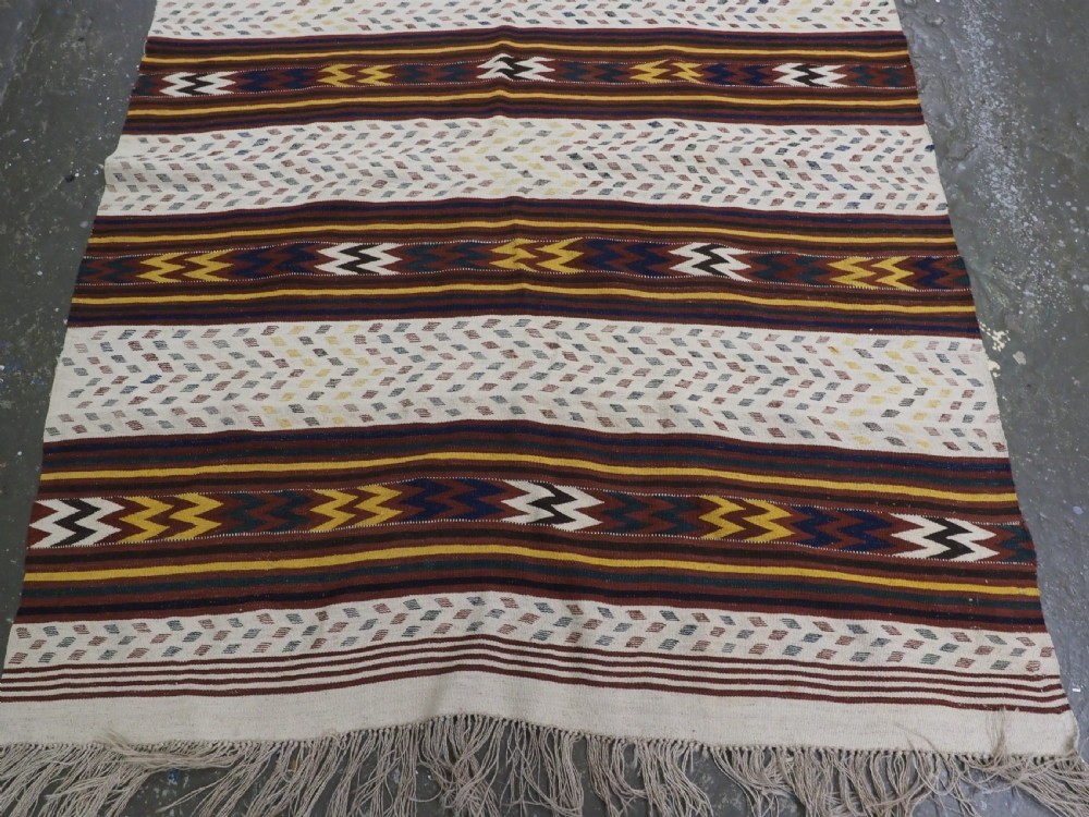 A long handwoven flatweave Central Asian kilim runner displaying cream sections alternating with dark brown, yellow, and red geometric bands with fringe at both ends. View VII