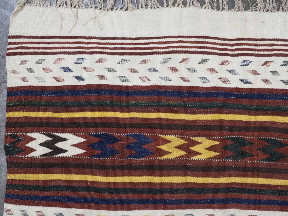 A long handwoven flatweave Central Asian kilim runner displaying cream sections alternating with dark brown, yellow, and red geometric bands with fringe at both ends. View VIII