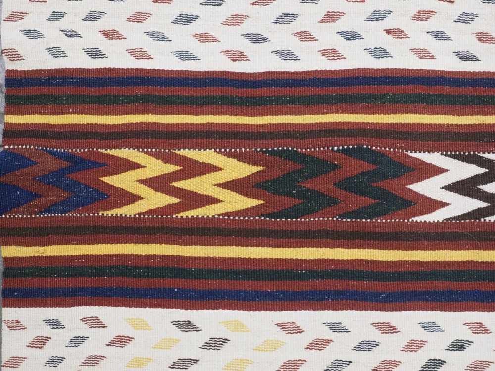 A long handwoven flatweave Central Asian kilim runner displaying cream sections alternating with dark brown, yellow, and red geometric bands with fringe at both ends. View IX
