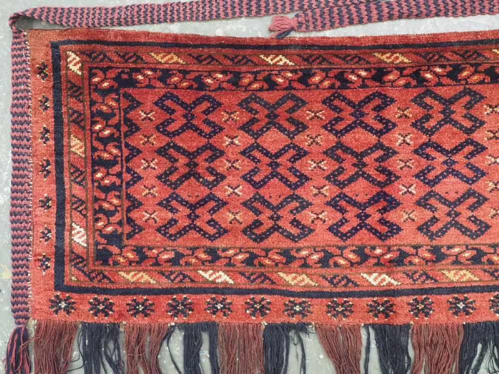 A hand-woven antique red wool Ersari Turkmen torba featuring geometric rams horn motifs, a long fringed lower edge, and braided side straps. View II