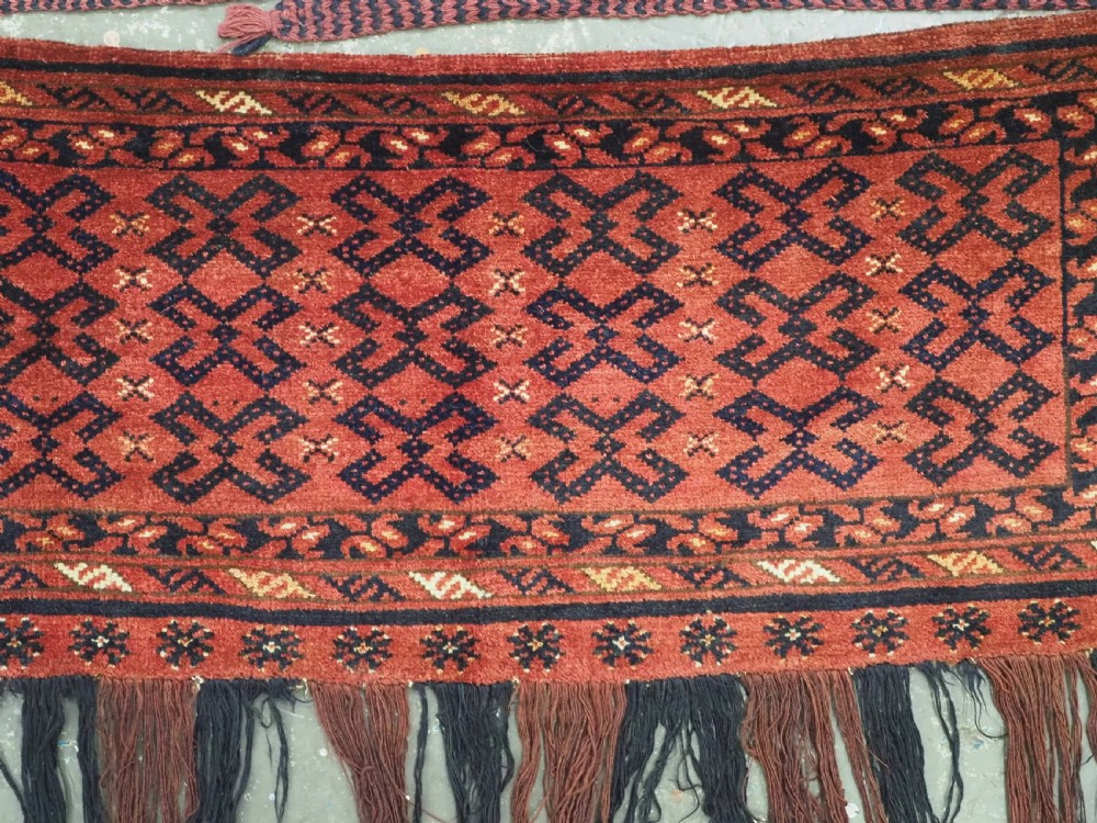 A hand-woven antique red wool Ersari Turkmen torba featuring geometric rams horn motifs, a long fringed lower edge, and braided side straps. View III