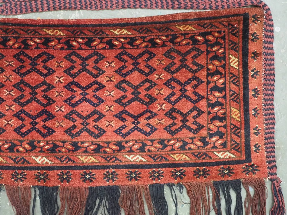 A hand-woven antique red wool Ersari Turkmen torba featuring geometric rams horn motifs, a long fringed lower edge, and braided side straps. View IV