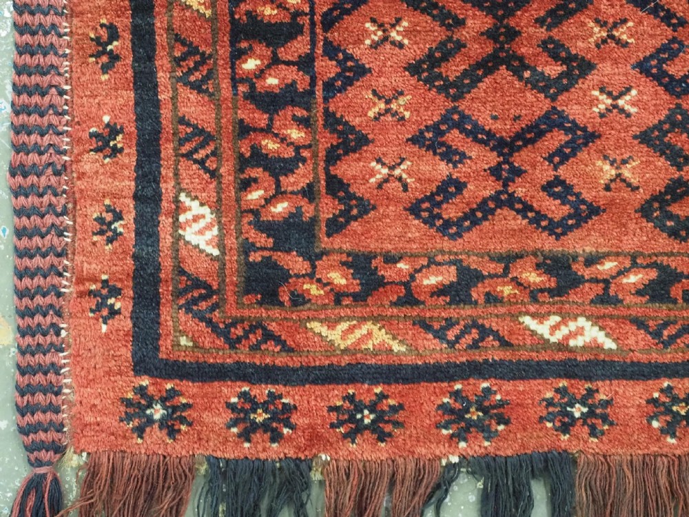 A hand-woven antique red wool Ersari Turkmen torba featuring geometric rams horn motifs, a long fringed lower edge, and braided side straps. View V