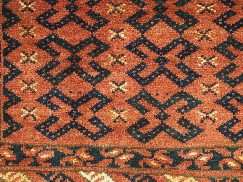A hand-woven antique red wool Ersari Turkmen torba featuring geometric rams horn motifs, a long fringed lower edge, and braided side straps. View VI