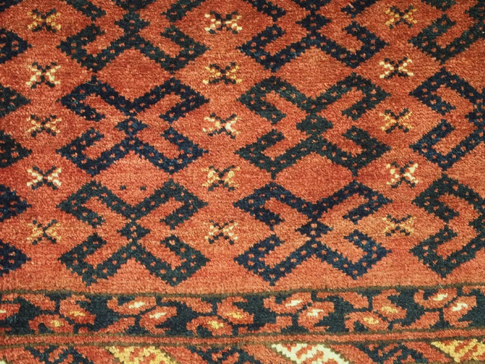 A hand-woven antique red wool Ersari Turkmen torba featuring geometric rams horn motifs, a long fringed lower edge, and braided side straps. View VII