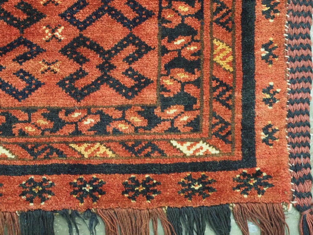 A hand-woven antique red wool Ersari Turkmen torba featuring geometric rams horn motifs, a long fringed lower edge, and braided side straps. View VIII