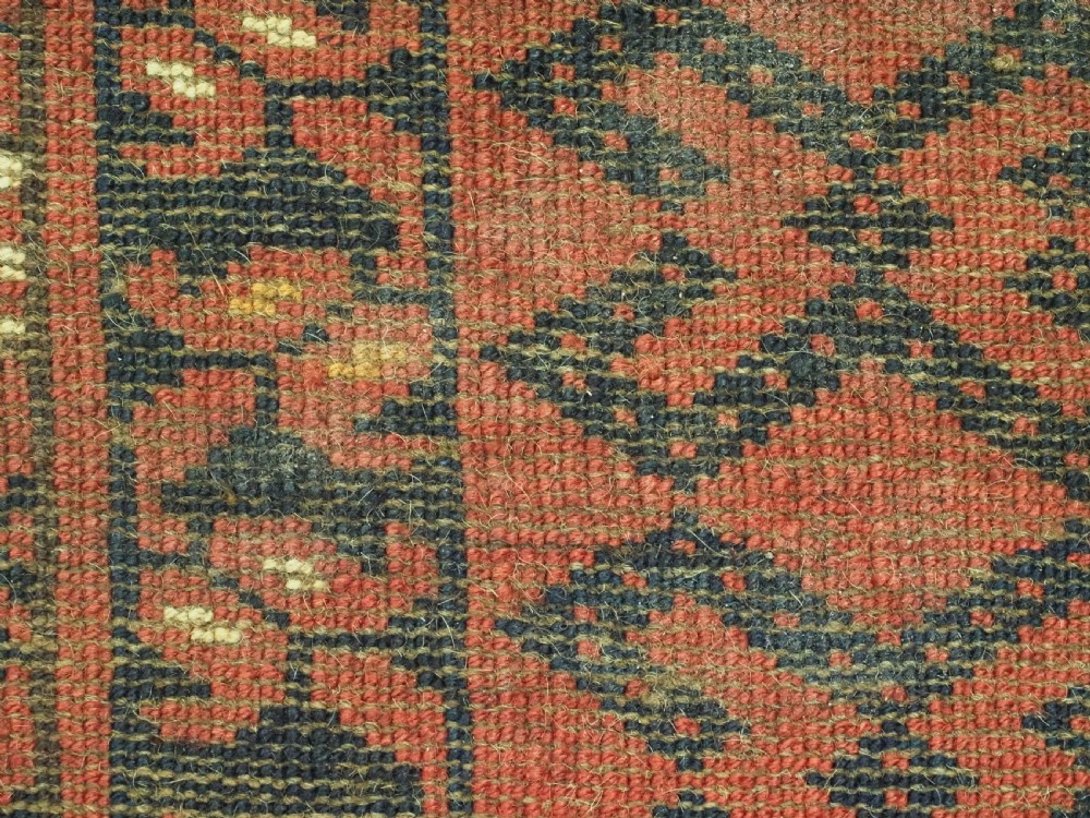 A hand-woven antique red wool Ersari Turkmen torba featuring geometric rams horn motifs, a long fringed lower edge, and braided side straps. View IX