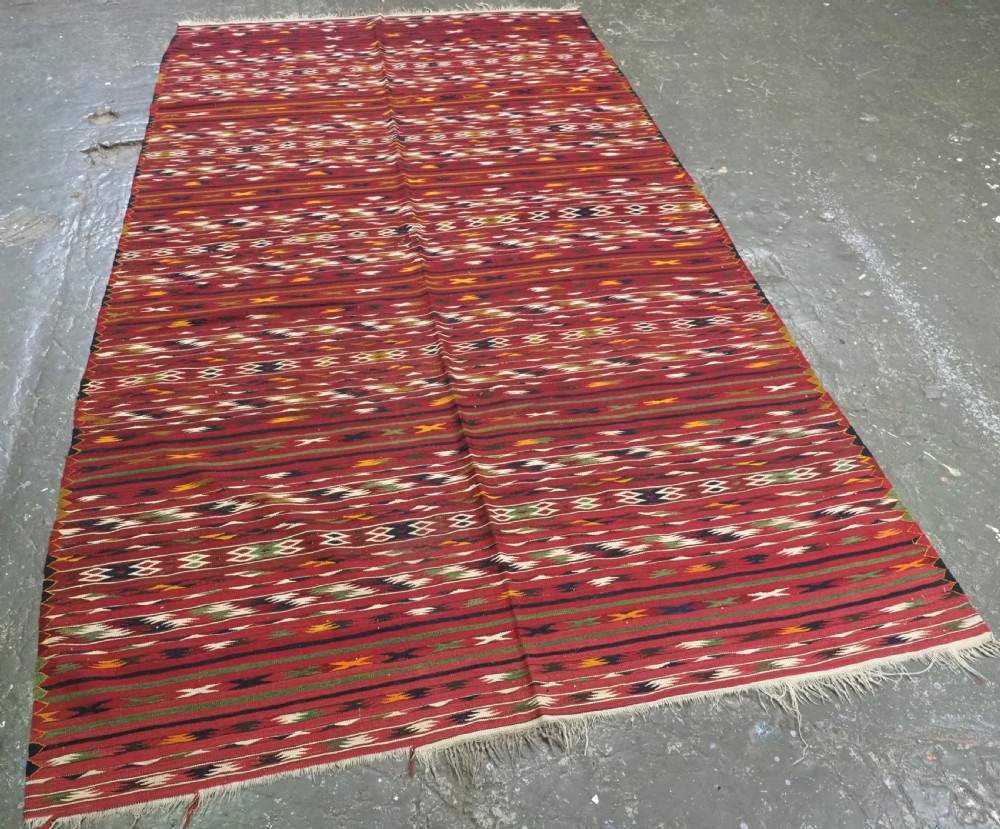 An antique flatweave Turkmen Dali kilim rug featuring horizontal bands of geometric motifs in red, cream, yellow, and dark green shades with fringed ends. View II