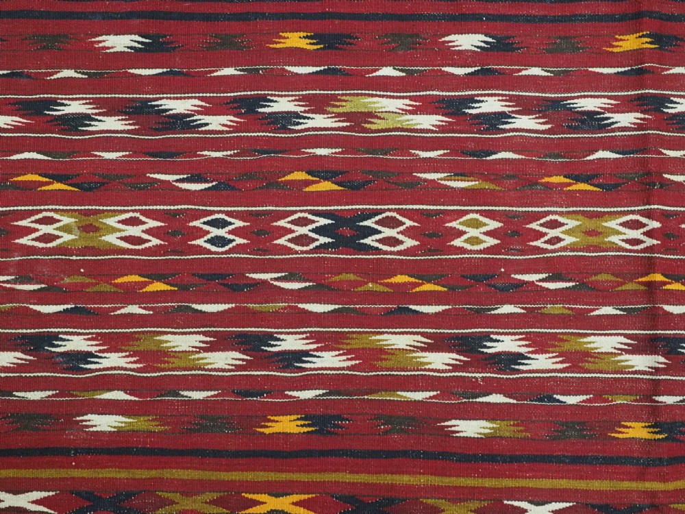 An antique flatweave Turkmen Dali kilim rug featuring horizontal bands of geometric motifs in red, cream, yellow, and dark green shades with fringed ends. View VIII