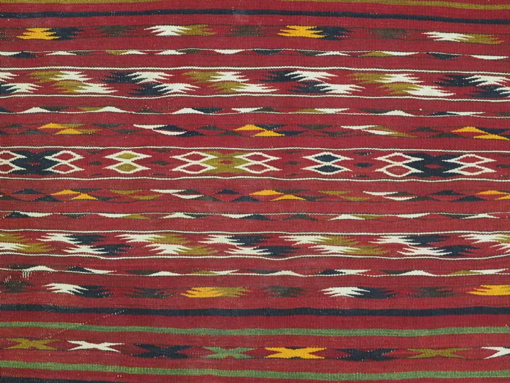 An antique flatweave Turkmen Dali kilim rug featuring horizontal bands of geometric motifs in red, cream, yellow, and dark green shades with fringed ends. View IX
