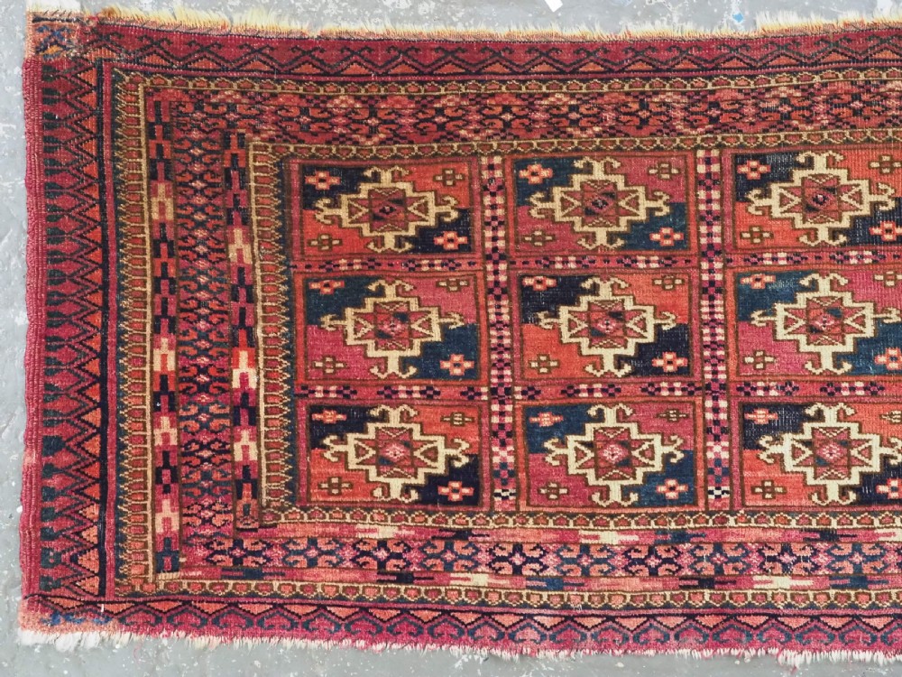 A small rectangular antique Tekke Turkmen mafrash wool panel featuring a repeating grid of geometric aina gul motifs in deep red, dark blue, and cream. View II