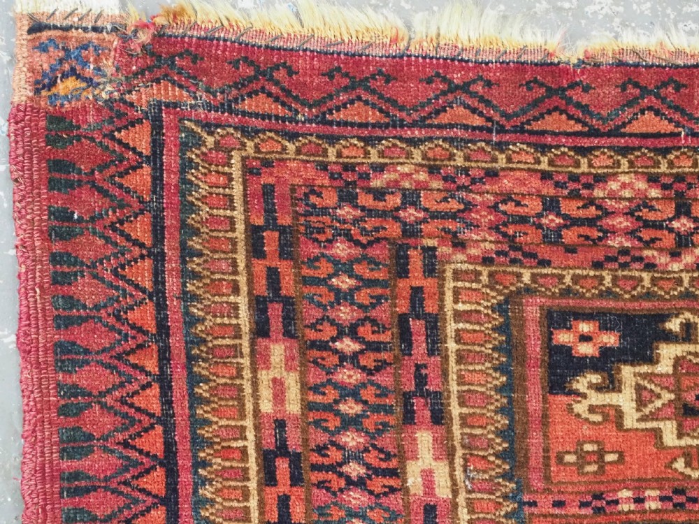 A small rectangular antique Tekke Turkmen mafrash wool panel featuring a repeating grid of geometric aina gul motifs in deep red, dark blue, and cream. View VI