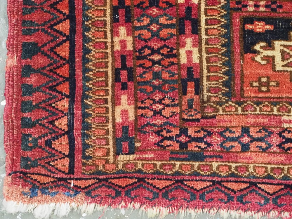A small rectangular antique Tekke Turkmen mafrash wool panel featuring a repeating grid of geometric aina gul motifs in deep red, dark blue, and cream. View VII