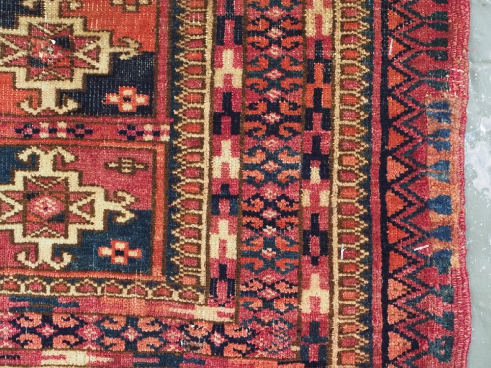 A small rectangular antique Tekke Turkmen mafrash wool panel featuring a repeating grid of geometric aina gul motifs in deep red, dark blue, and cream. View IX