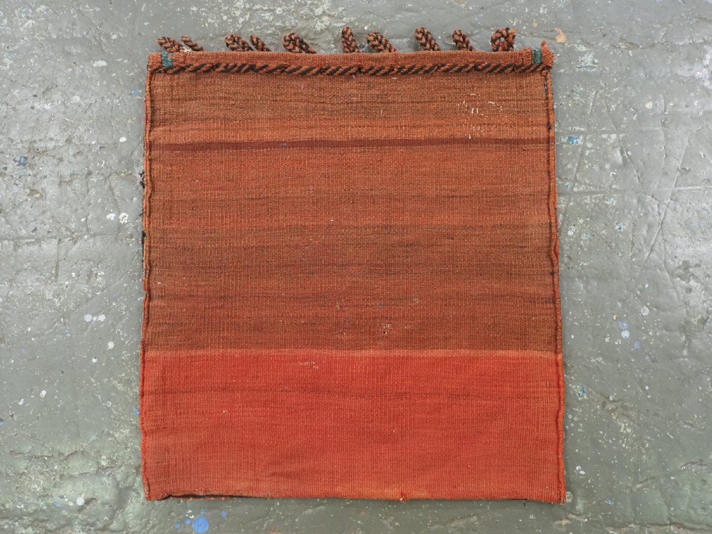 A square handwoven wool Khamseh saddlebag face featuring geometric diamond medallions in terracotta red, cream, and blue set against a dark navy ground with a multi-bordered frame. View X