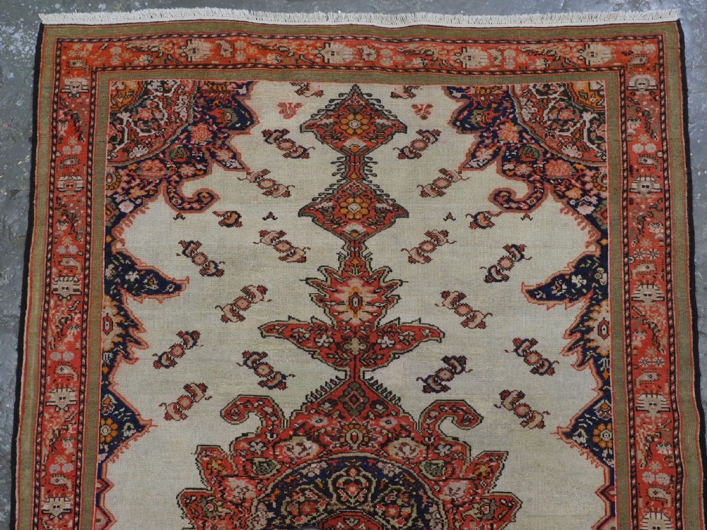 An antique Persian Malayer hand-knotted wool rug featuring an ivory central field, a complex terracotta and navy medallion, butterfly motifs, and a detailed multi-stripe border. View III