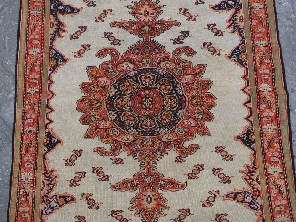 An antique Persian Malayer hand-knotted wool rug featuring an ivory central field, a complex terracotta and navy medallion, butterfly motifs, and a detailed multi-stripe border. View IV