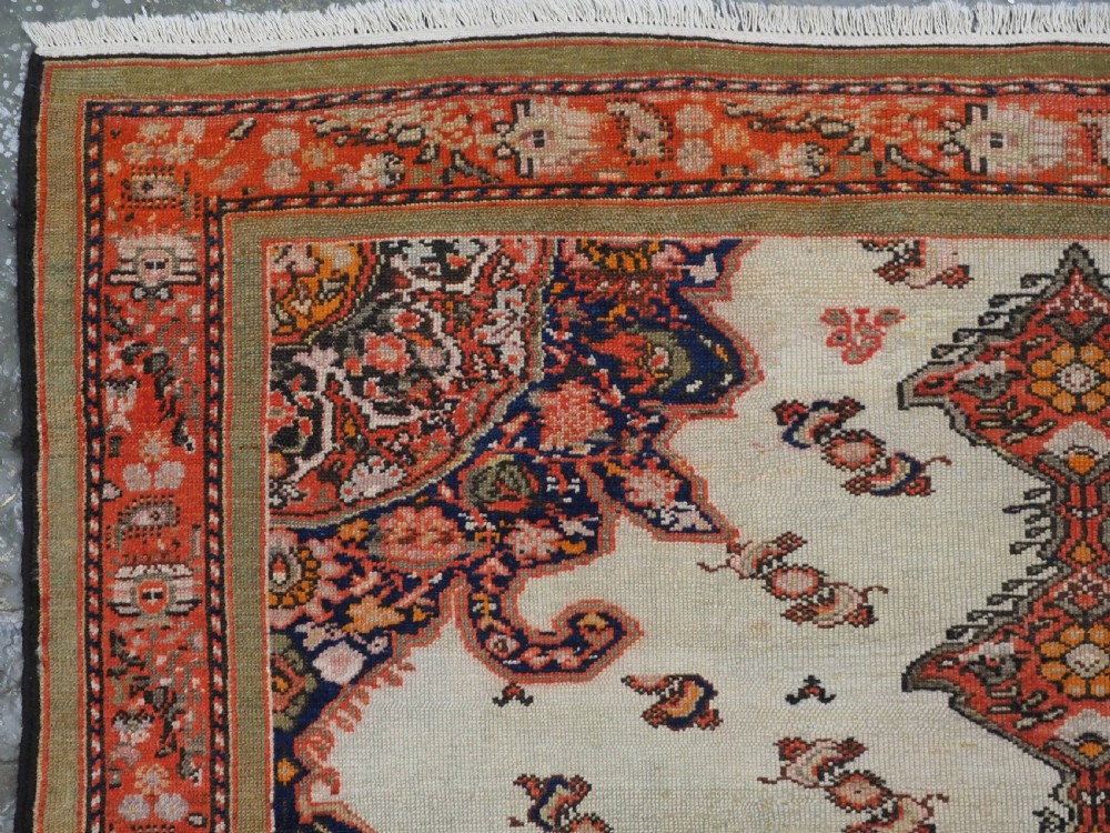 An antique Persian Malayer hand-knotted wool rug featuring an ivory central field, a complex terracotta and navy medallion, butterfly motifs, and a detailed multi-stripe border. View VI