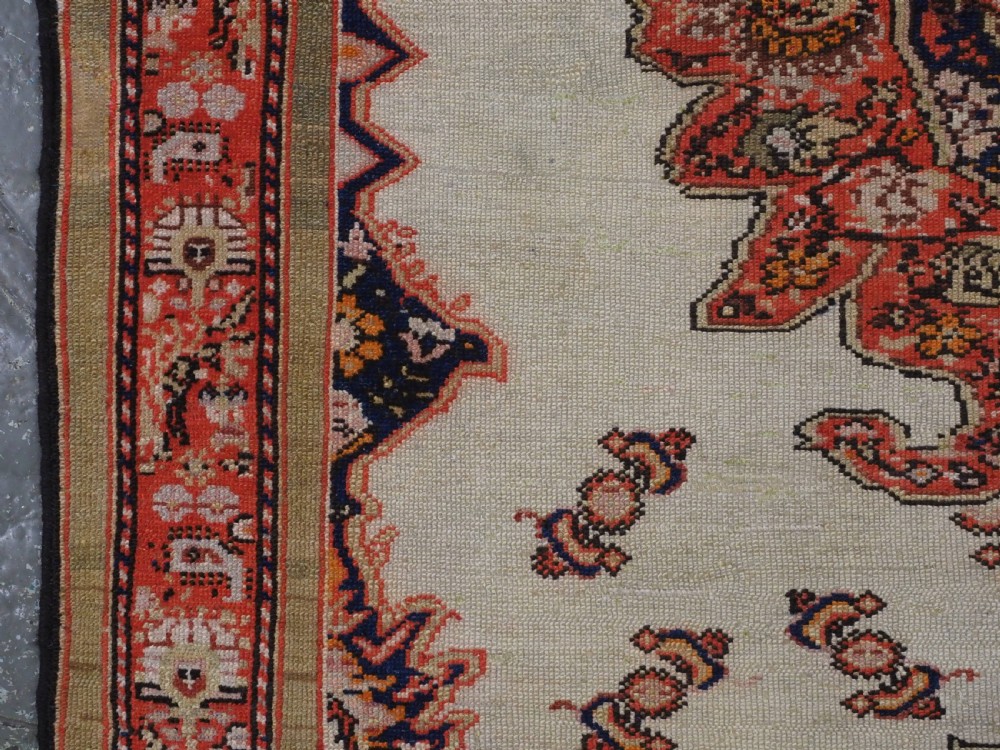 An antique Persian Malayer hand-knotted wool rug featuring an ivory central field, a complex terracotta and navy medallion, butterfly motifs, and a detailed multi-stripe border. View VII
