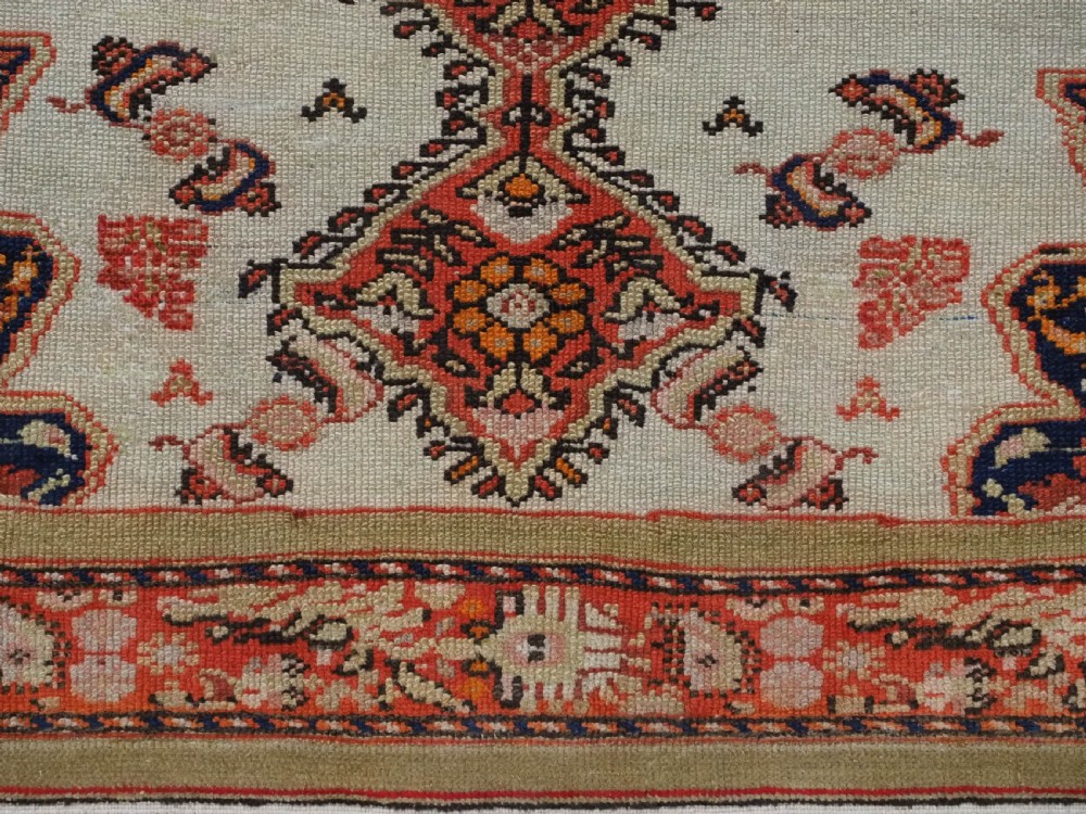 An antique Persian Malayer hand-knotted wool rug featuring an ivory central field, a complex terracotta and navy medallion, butterfly motifs, and a detailed multi-stripe border. View XIV