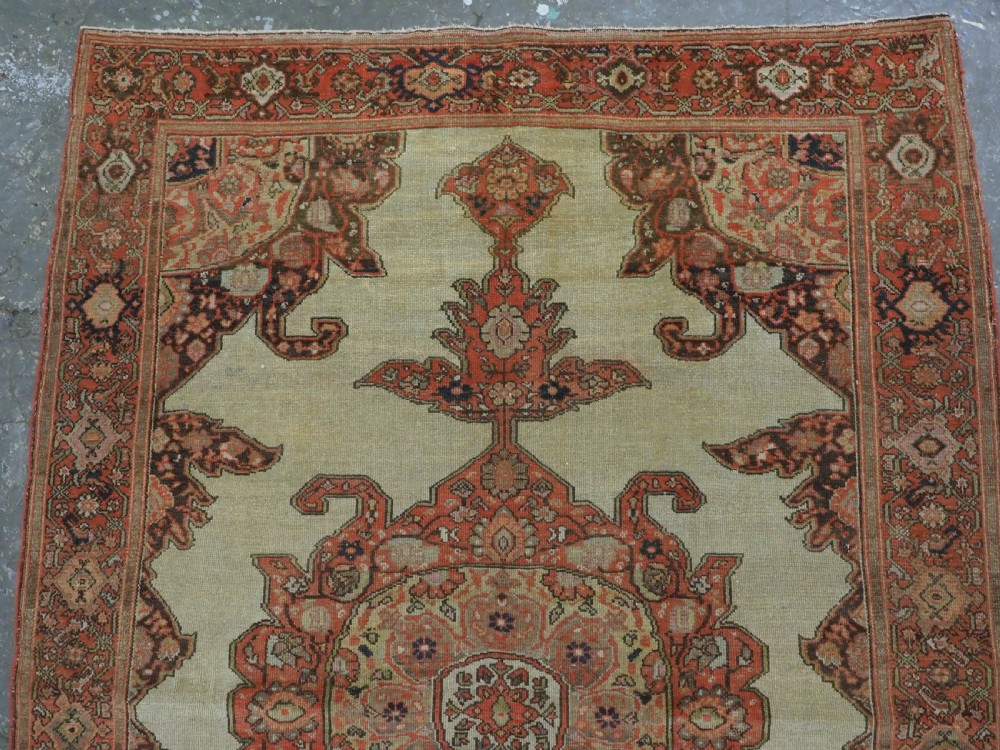 An antique hand-knotted Persian Malayer rug featuring a central terracotta medallion on a cream field with geometric patterned borders. View III