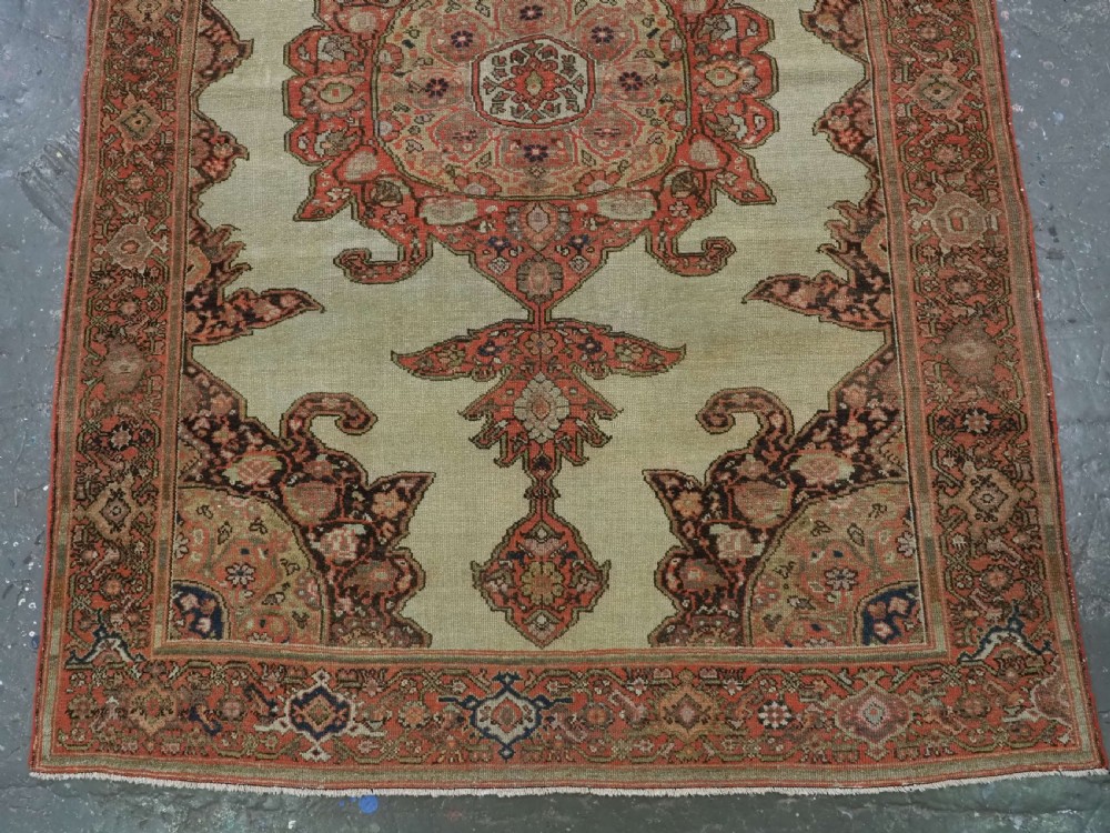 An antique hand-knotted Persian Malayer rug featuring a central terracotta medallion on a cream field with geometric patterned borders. View V