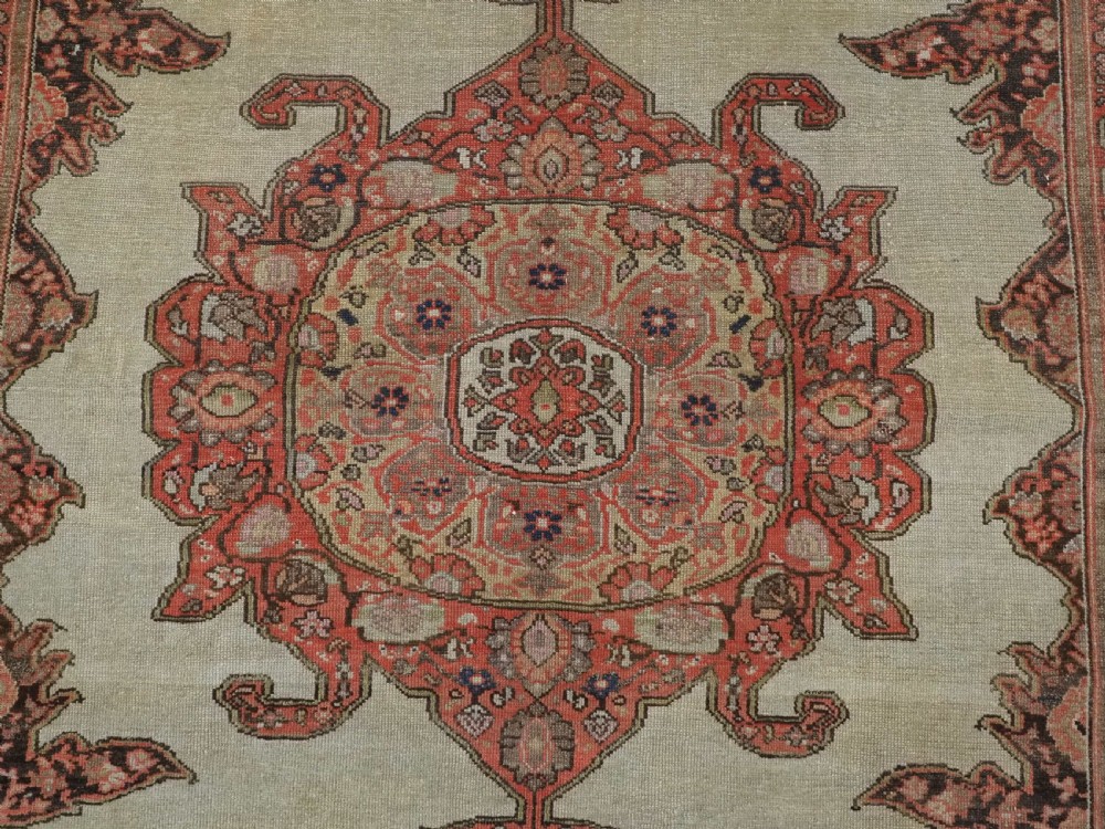 An antique hand-knotted Persian Malayer rug featuring a central terracotta medallion on a cream field with geometric patterned borders. View IX
