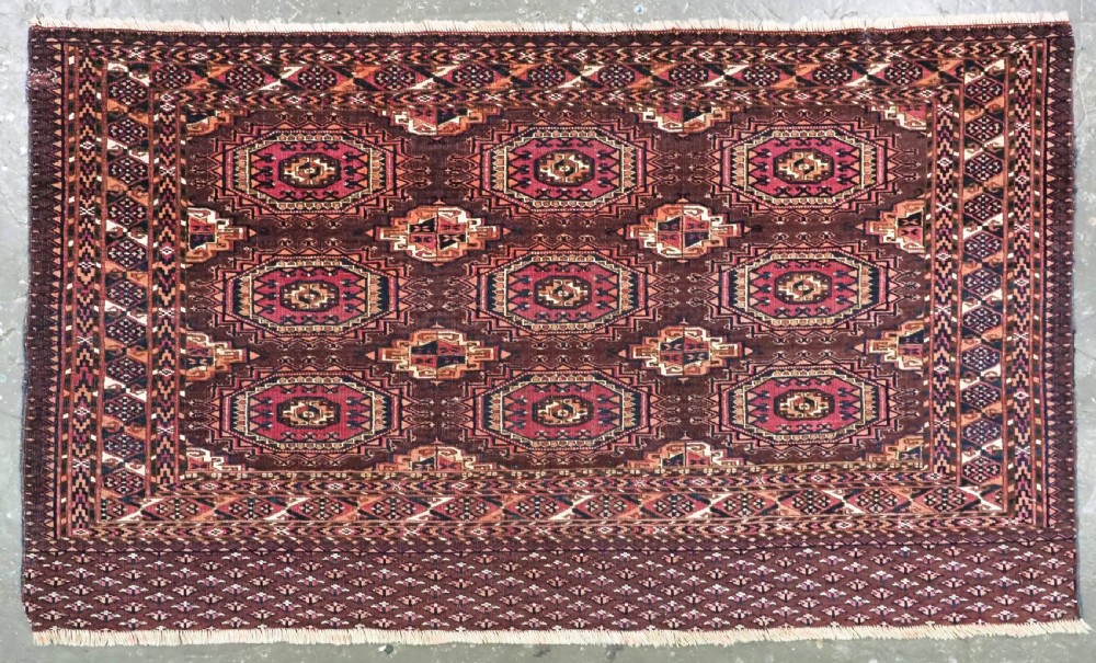 An antique Saryk Turkmen chuval face featuring nine octagonal Salor guls in deep crimson, brown, and white with geometric borders.