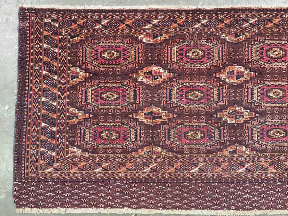 An antique Saryk Turkmen chuval face featuring nine octagonal Salor guls in deep crimson, brown, and white with geometric borders. View II