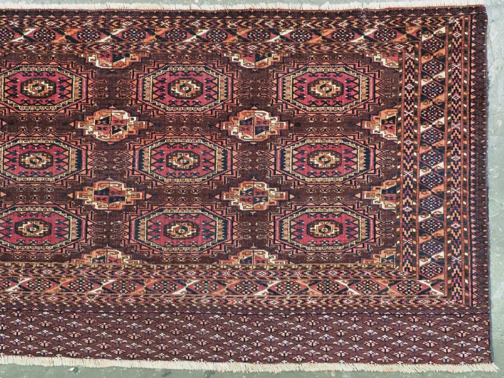 An antique Saryk Turkmen chuval face featuring nine octagonal Salor guls in deep crimson, brown, and white with geometric borders. View III