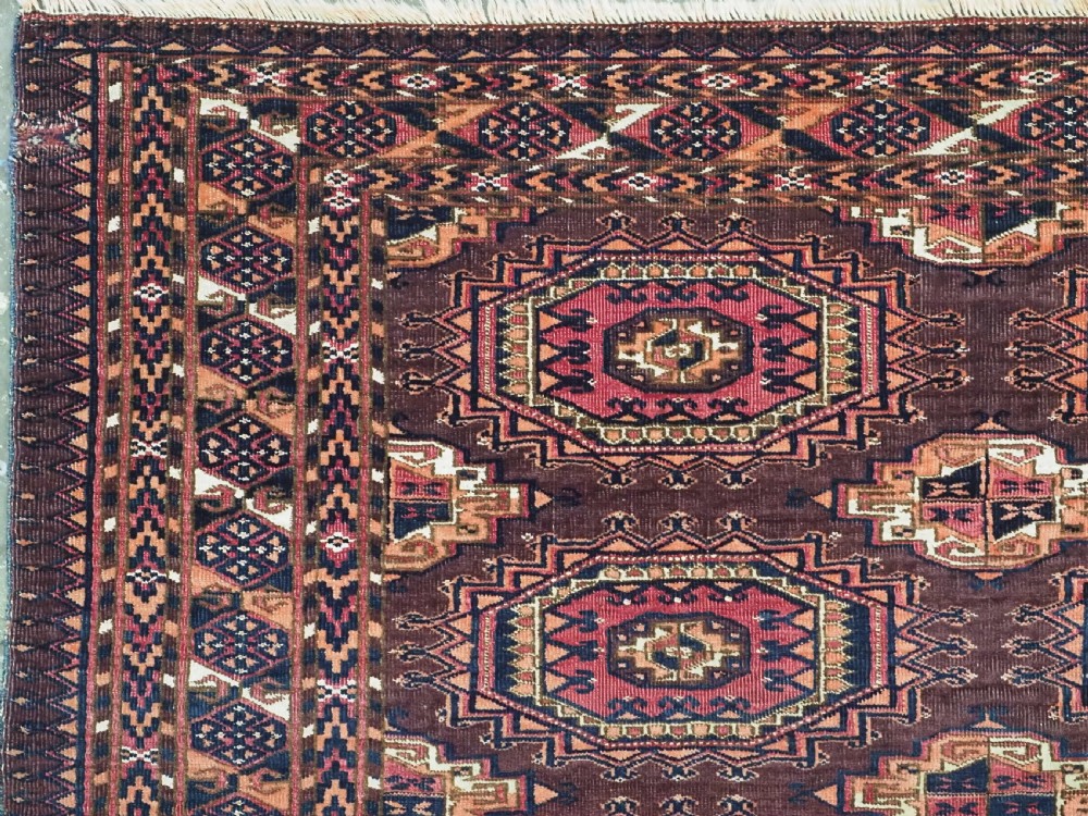 An antique Saryk Turkmen chuval face featuring nine octagonal Salor guls in deep crimson, brown, and white with geometric borders. View IV