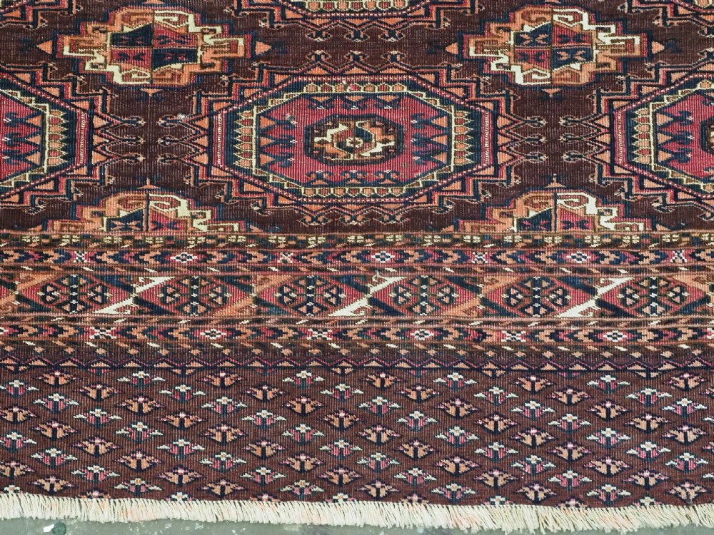 An antique Saryk Turkmen chuval face featuring nine octagonal Salor guls in deep crimson, brown, and white with geometric borders. View VII