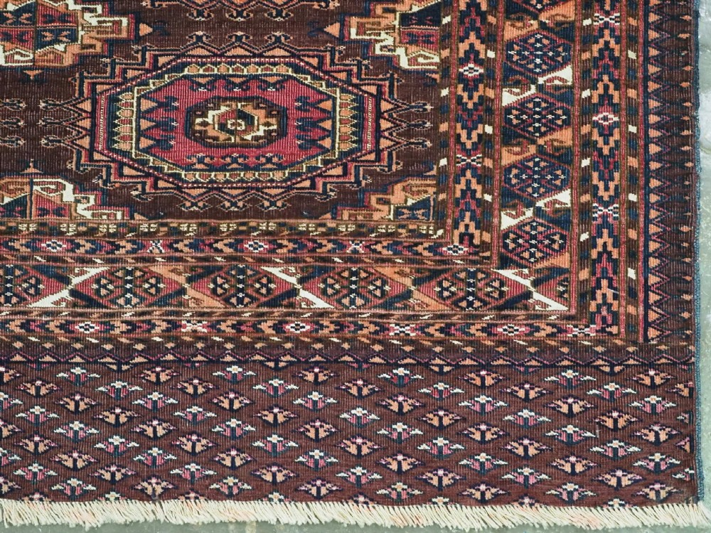 An antique Saryk Turkmen chuval face featuring nine octagonal Salor guls in deep crimson, brown, and white with geometric borders. View IX